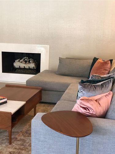 A living room with a couch, coffee table and fireplace.