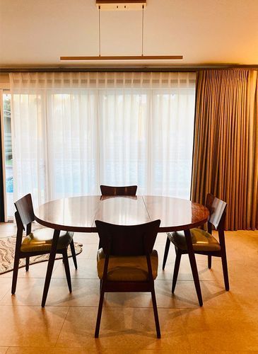 A dining room with a round table and chairs in front of a large window.