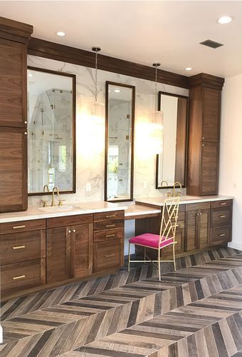 A bathroom with two sinks, two mirrors, and a pink chair.