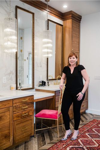 A woman is standing next to a chair in a bathroom.