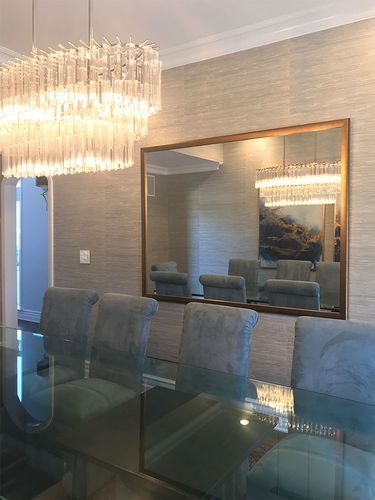 A dining room with a glass table and chairs and a large mirror.