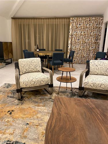 A living room with two chairs, a table, and a rug.