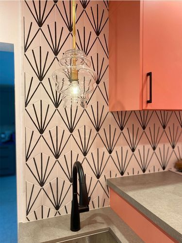 A kitchen with pink cabinets and a sink with a light hanging from the ceiling.