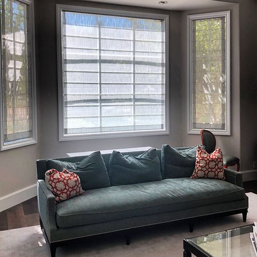 A living room with a couch, chair, table, and windows.
