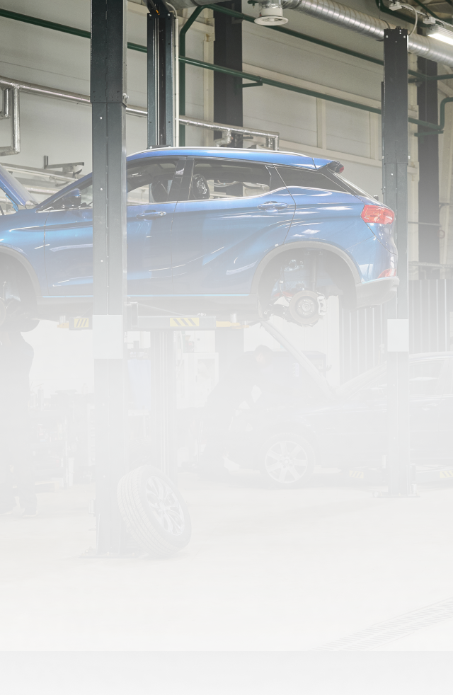 Blue SUV on a car lift in a garage, partially obscured by bright glare and haze | Universal Auto Repair