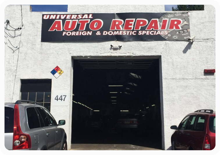 Auto repair shop entrance with open garage door, “Universal Auto Repair” sign, and parked cars on both sides | Universal Auto Repair