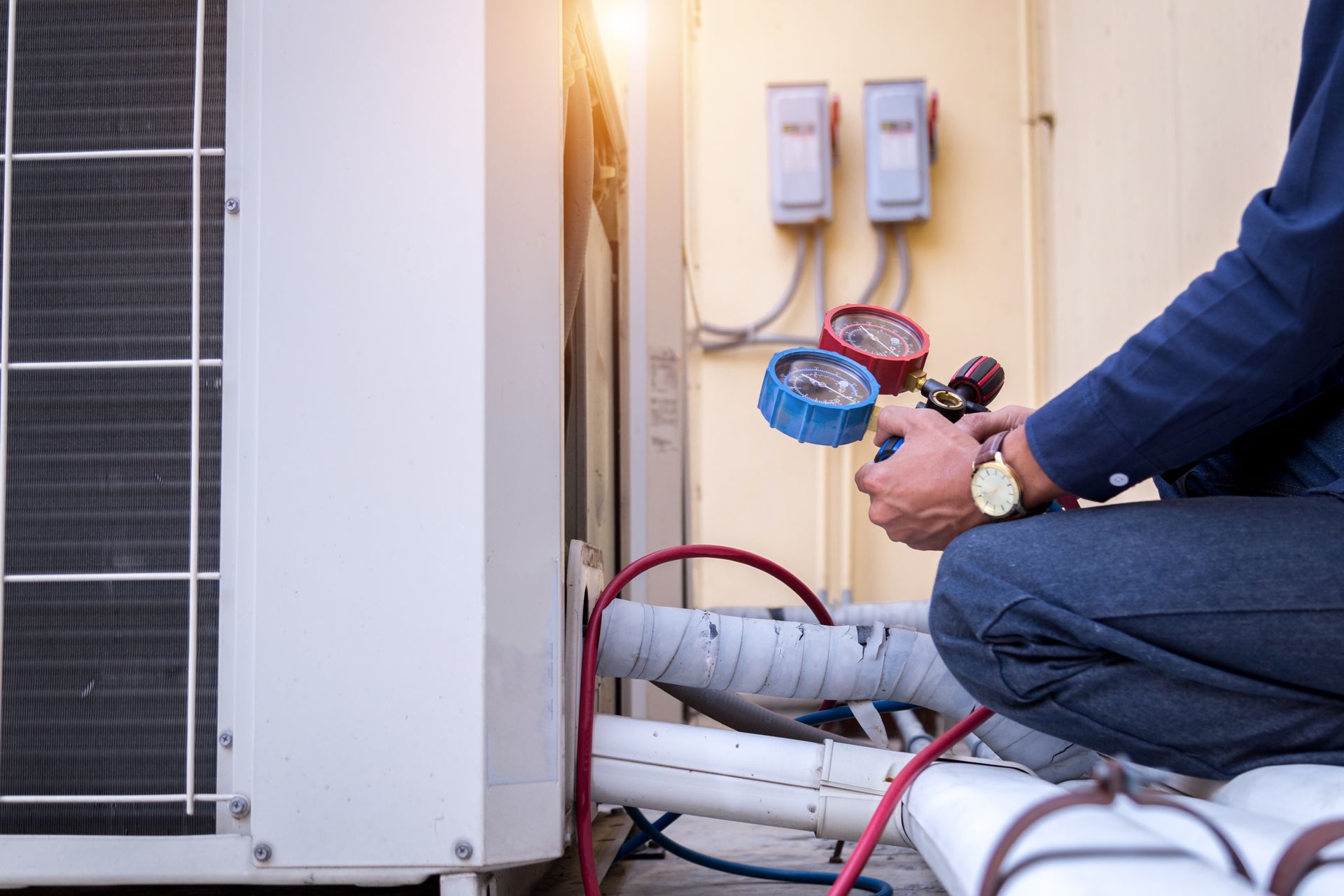 A man wearing a hard hat is working on an air conditioner.