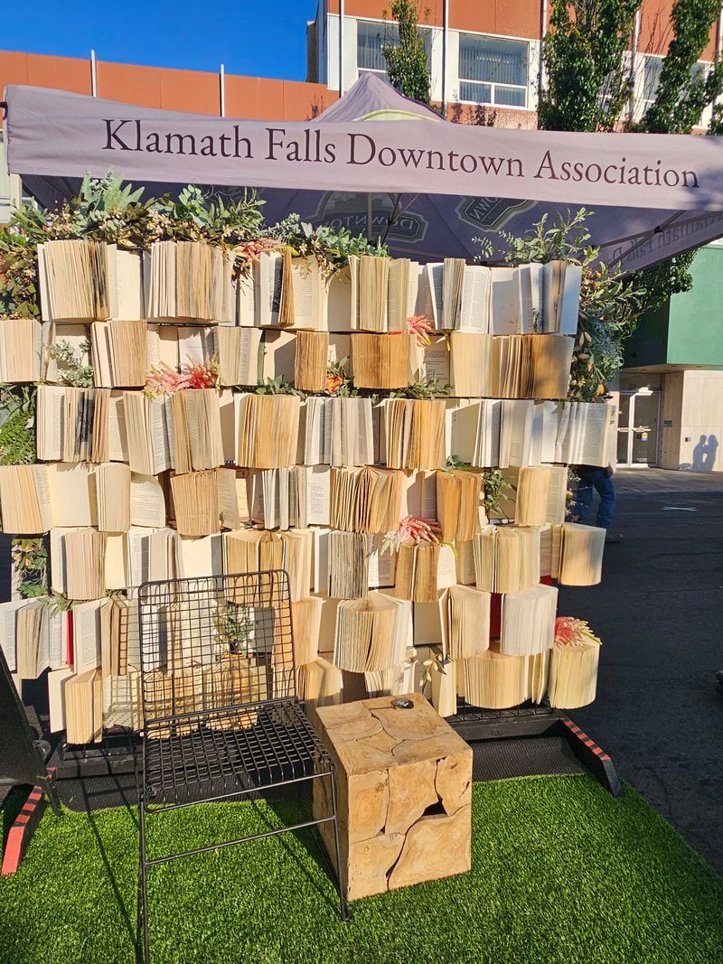 A wall made of books is sitting on top of a lush green field.