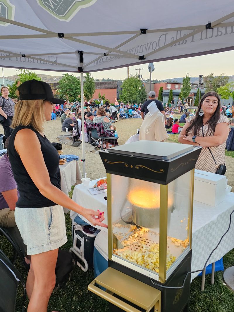 A woman is standing in front of a popcorn machine.