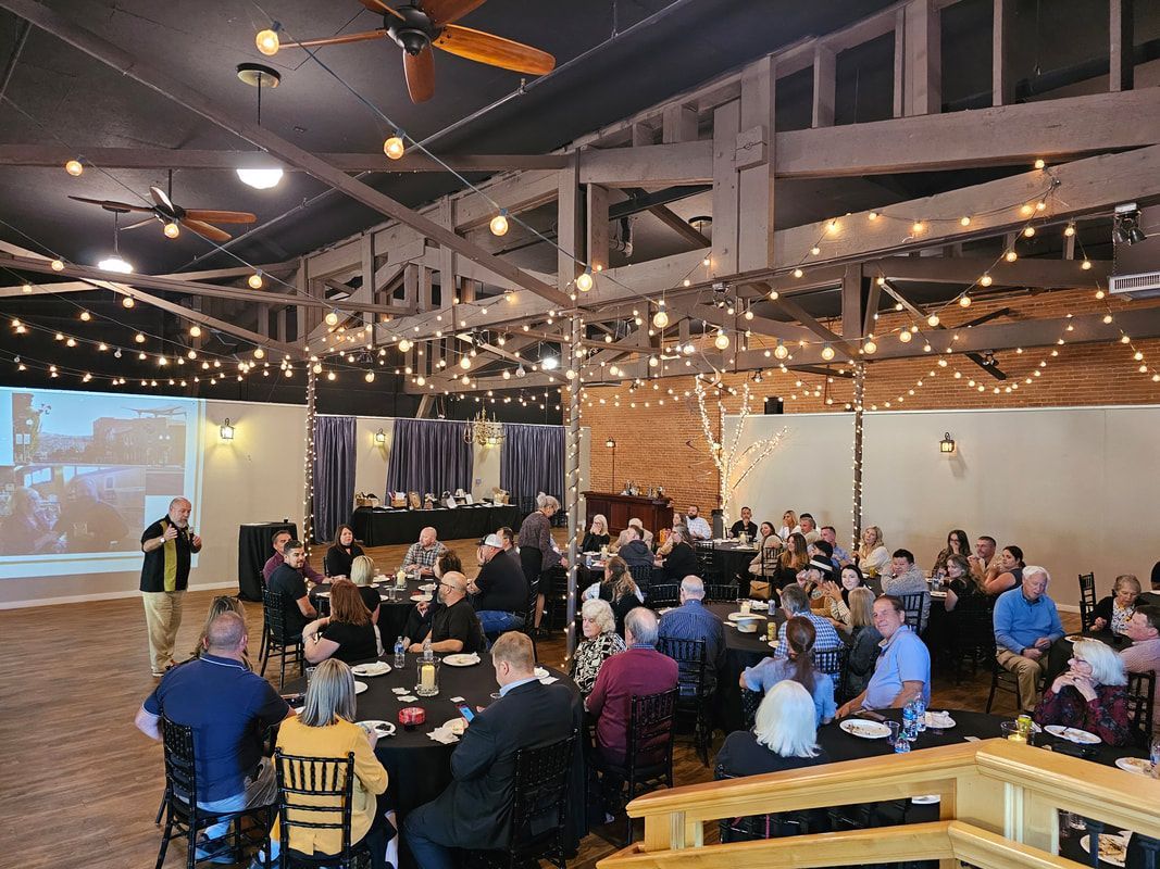 A large group of people are sitting at tables in a large room.