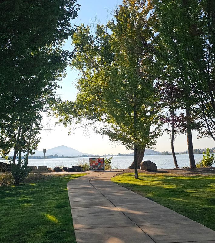 A concrete walkway leads to a lake surrounded by trees