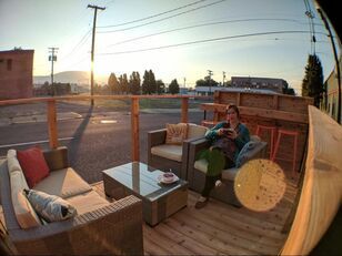 A woman is sitting on a couch on a deck reading a book.