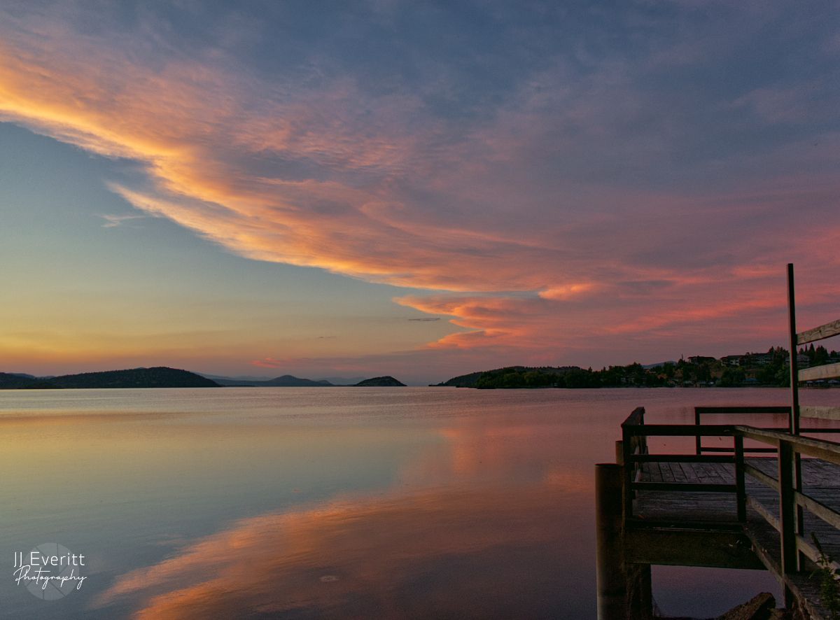 A woman is sitting on a couch on a deck reading a book.