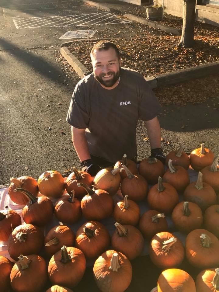 A man is standing in front of a table full of pumpkins