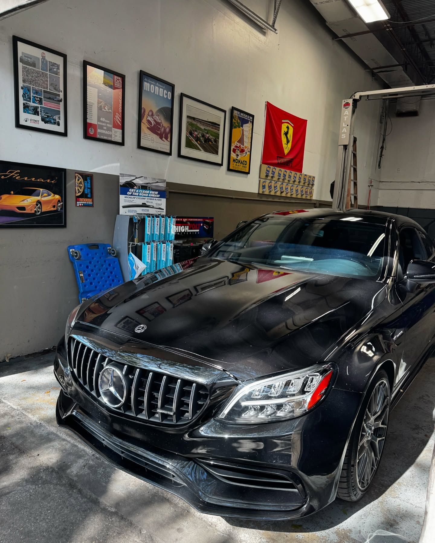Black BMW sports car with hood open, parked inside a garage.