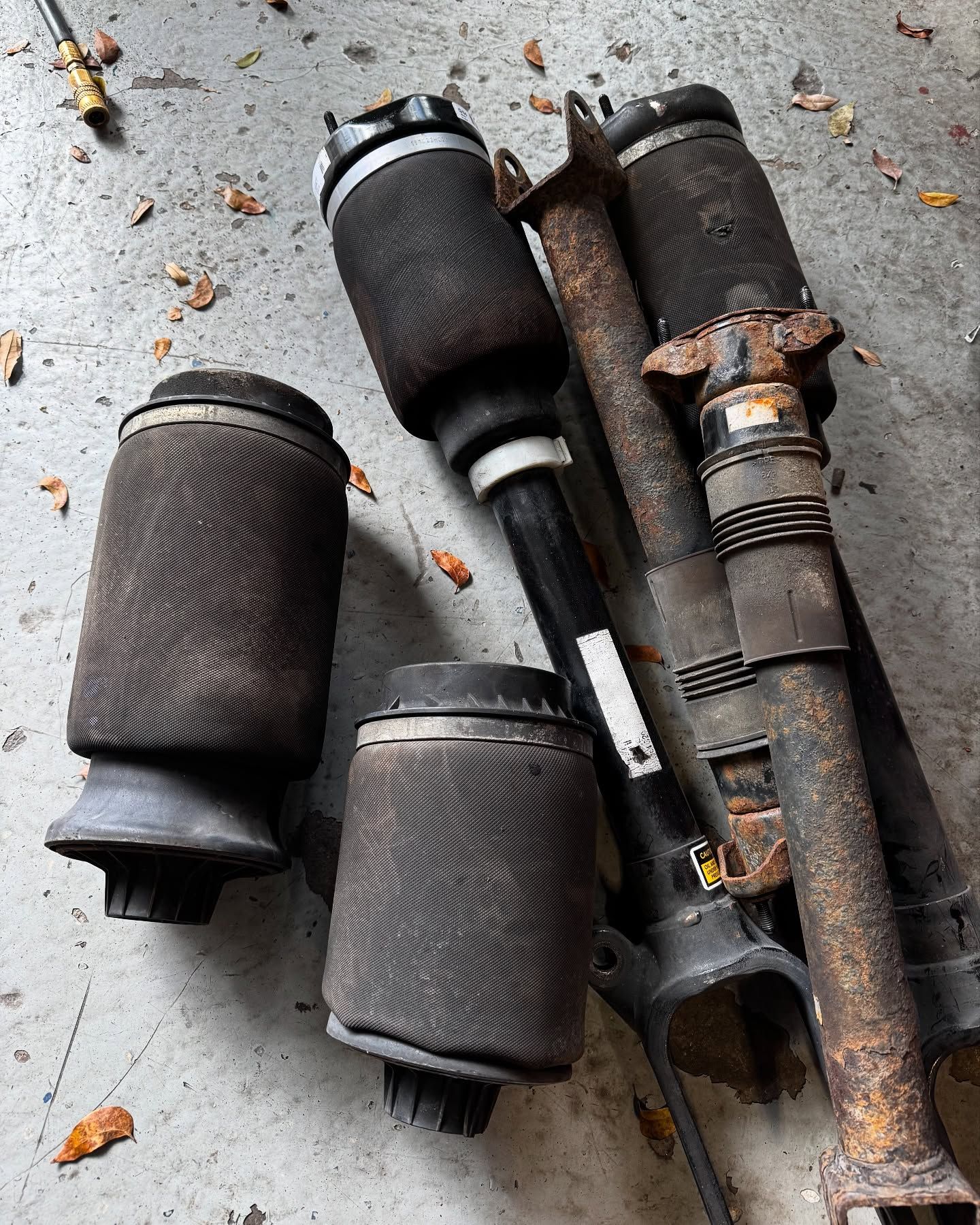 Several used air suspension components: air springs and struts lying on a concrete surface.