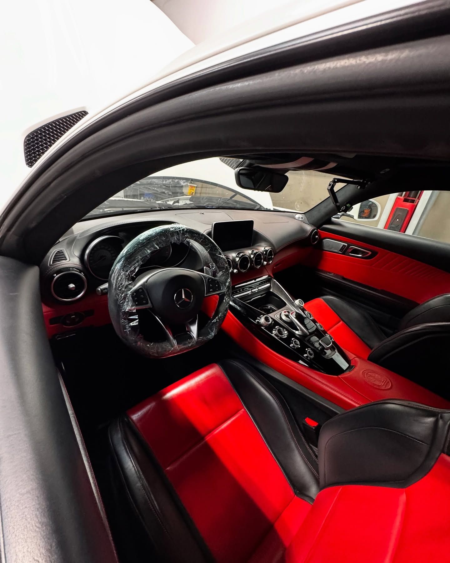 Red and black interior of a Mercedes-Benz sports car; steering wheel, seats, dashboard visible.
