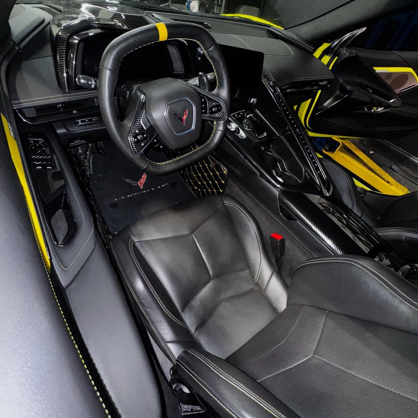 Black and yellow interior of a Corvette sports car. Black leather seats, steering wheel with yellow accent.