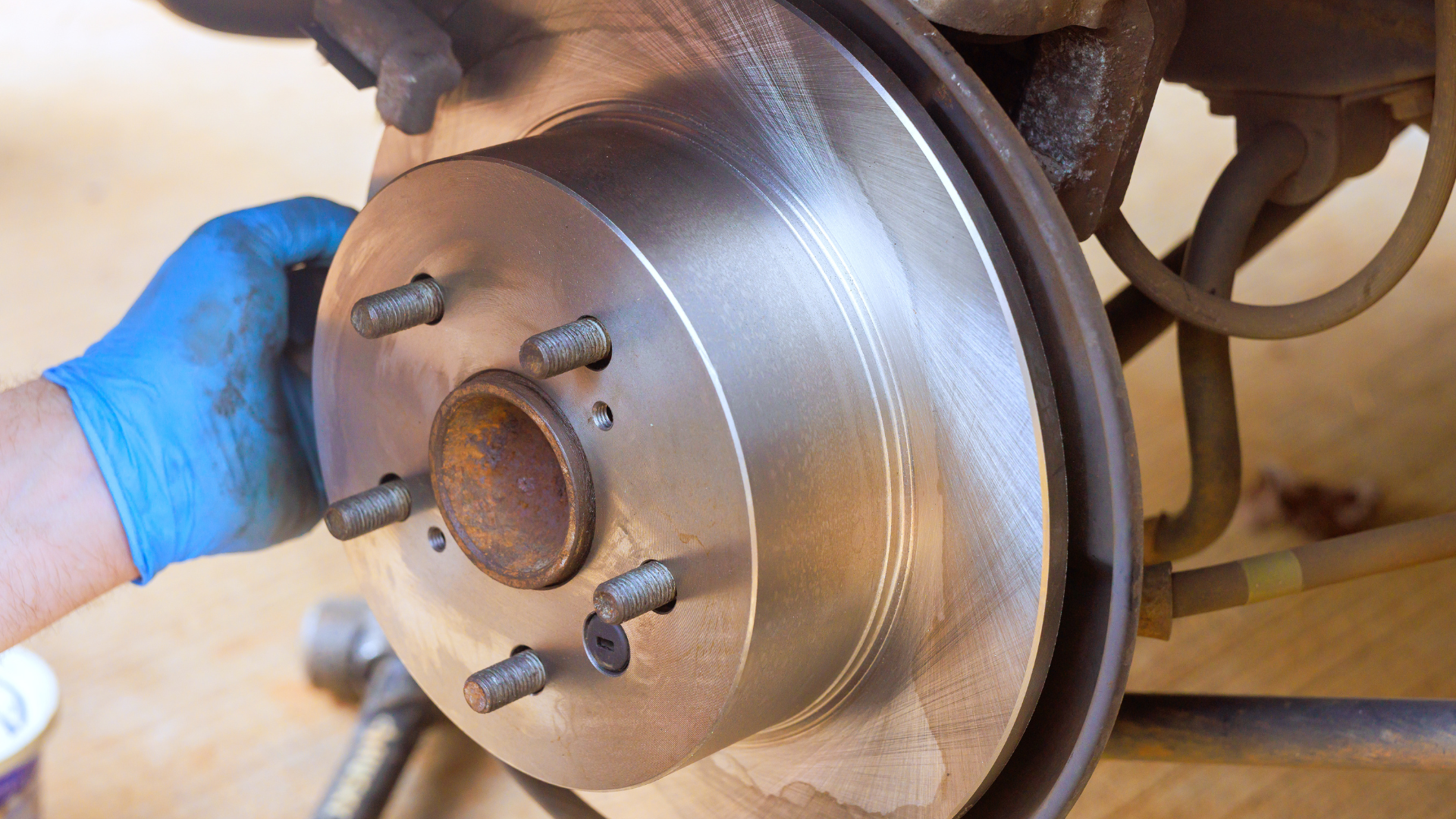 Mechanic in gloves working on a car engine with a wrench.