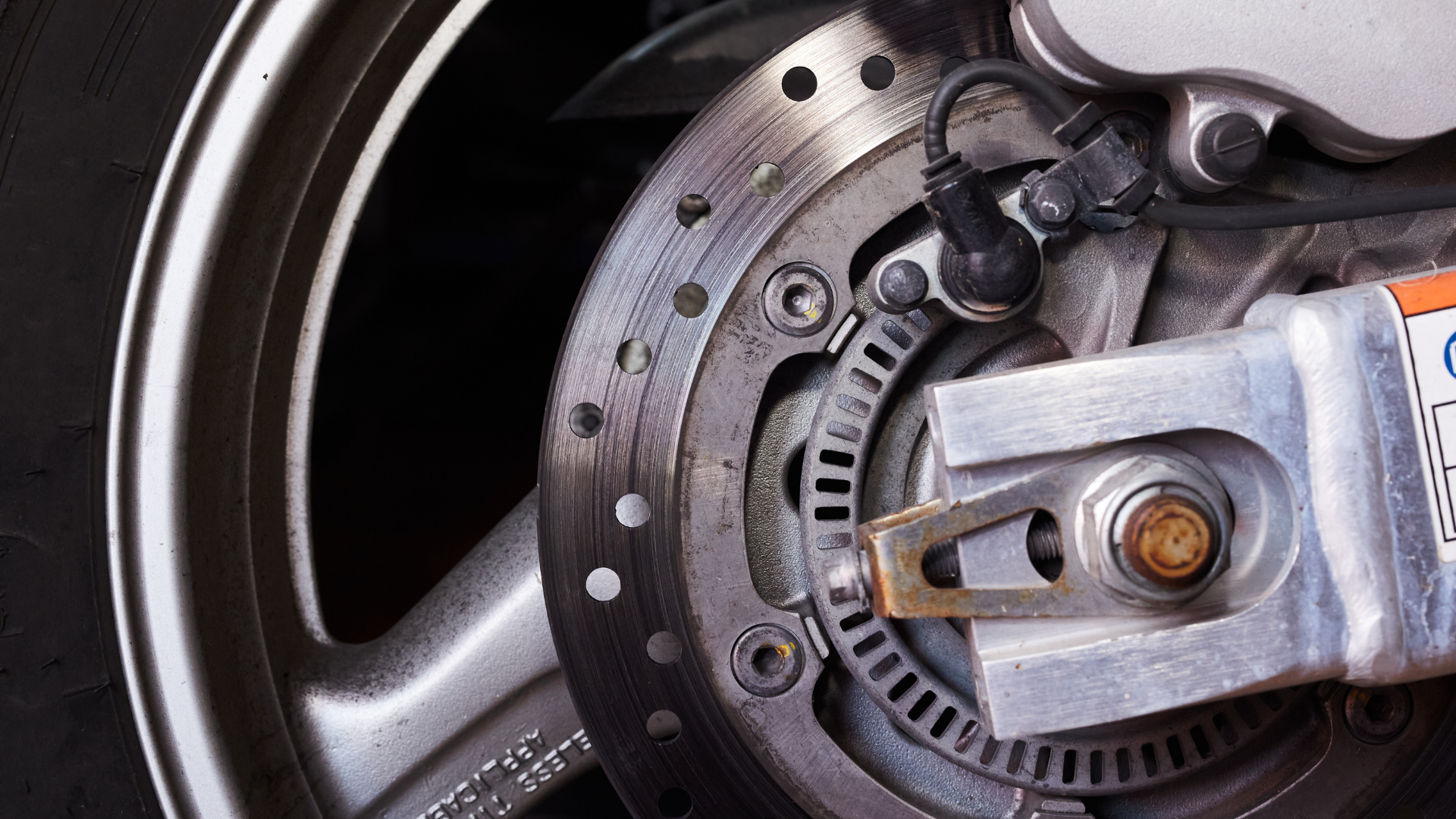 Person's hand reaching to open a black radiator cap in an engine bay.