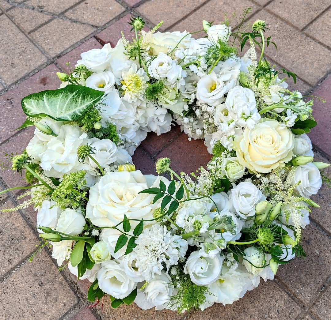 Ghirlanda floreale bianca su una superficie di mattoni.