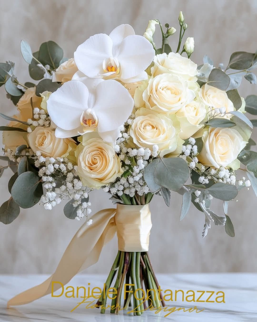 Bouquet di fiori bianchi e color pesca con orchidee, rose, eucalipto e un nastro dorato.