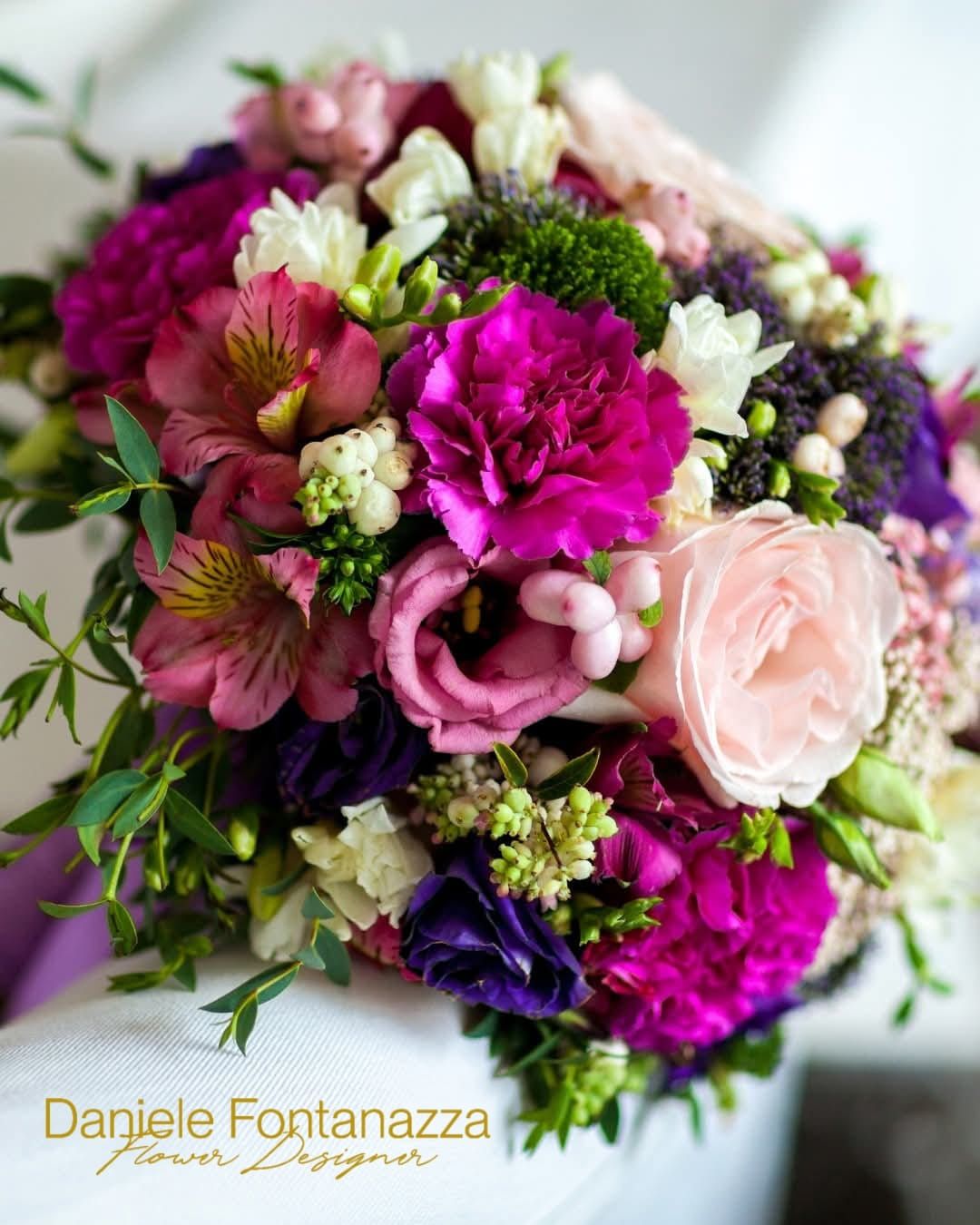 Bouquet di vivaci fiori rosa, viola e bianchi con verde, probabilmente per un'occasione speciale.