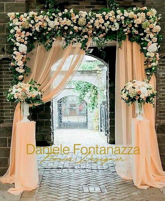 Arco floreale con drappeggio color pesca all'ingresso.