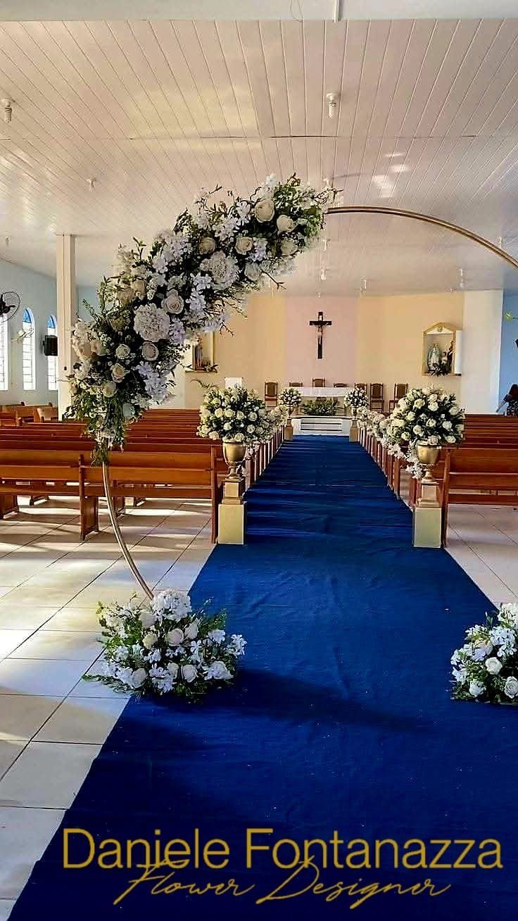 Navata della chiesa decorata con fiori bianchi e tappeto blu per una cerimonia nuziale.