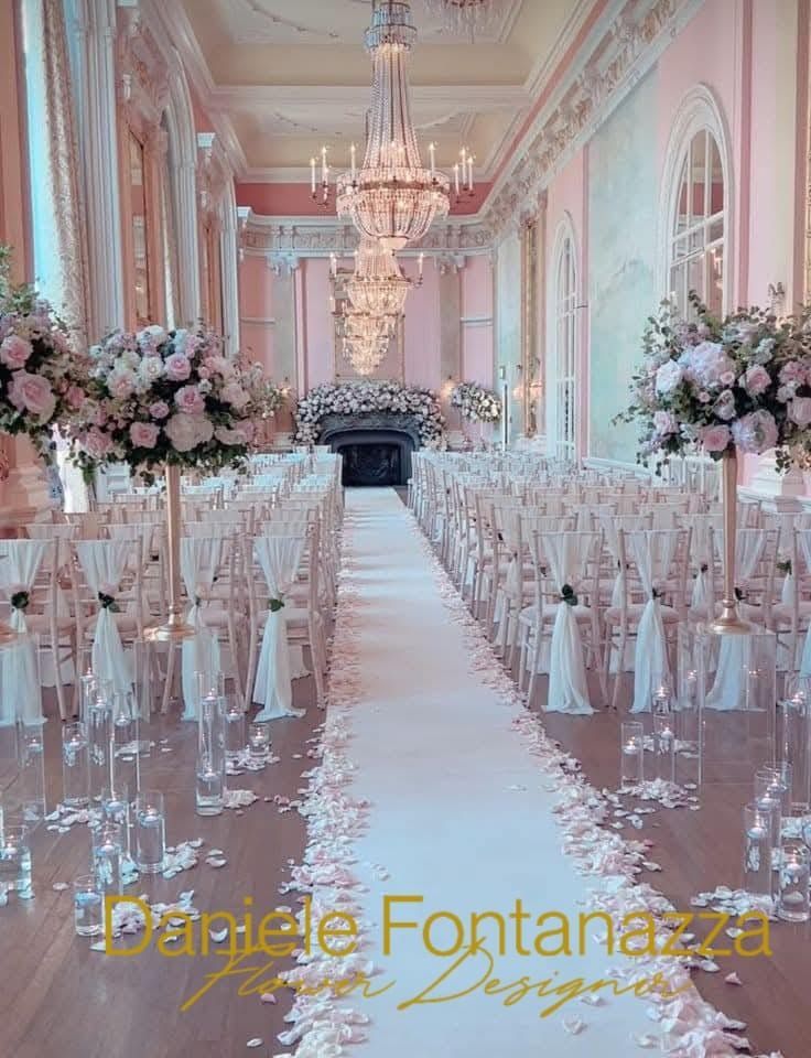 Elegante cerimonia nuziale allestita in una sala da ballo: sedie bianche, runner lungo la navata, composizioni floreali, lampadari.