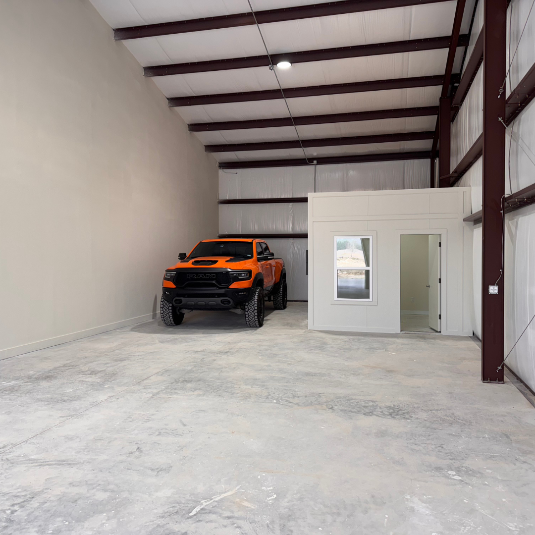 An orange truck is parked next to an office space in an empty garage