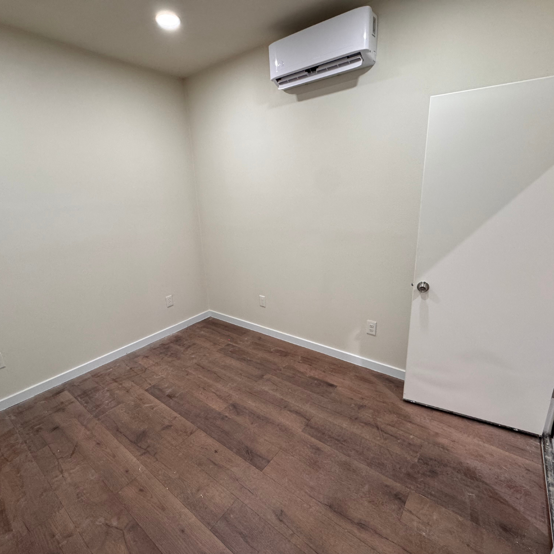 An empty office room with hardwood floors and a white door in BT Garages