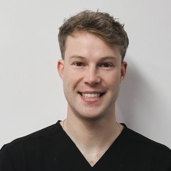 Man with fair skin and short, light brown hair, smiling at the camera, wearing a black shirt.