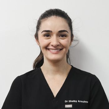 Woman in black scrubs smiles at the camera. 