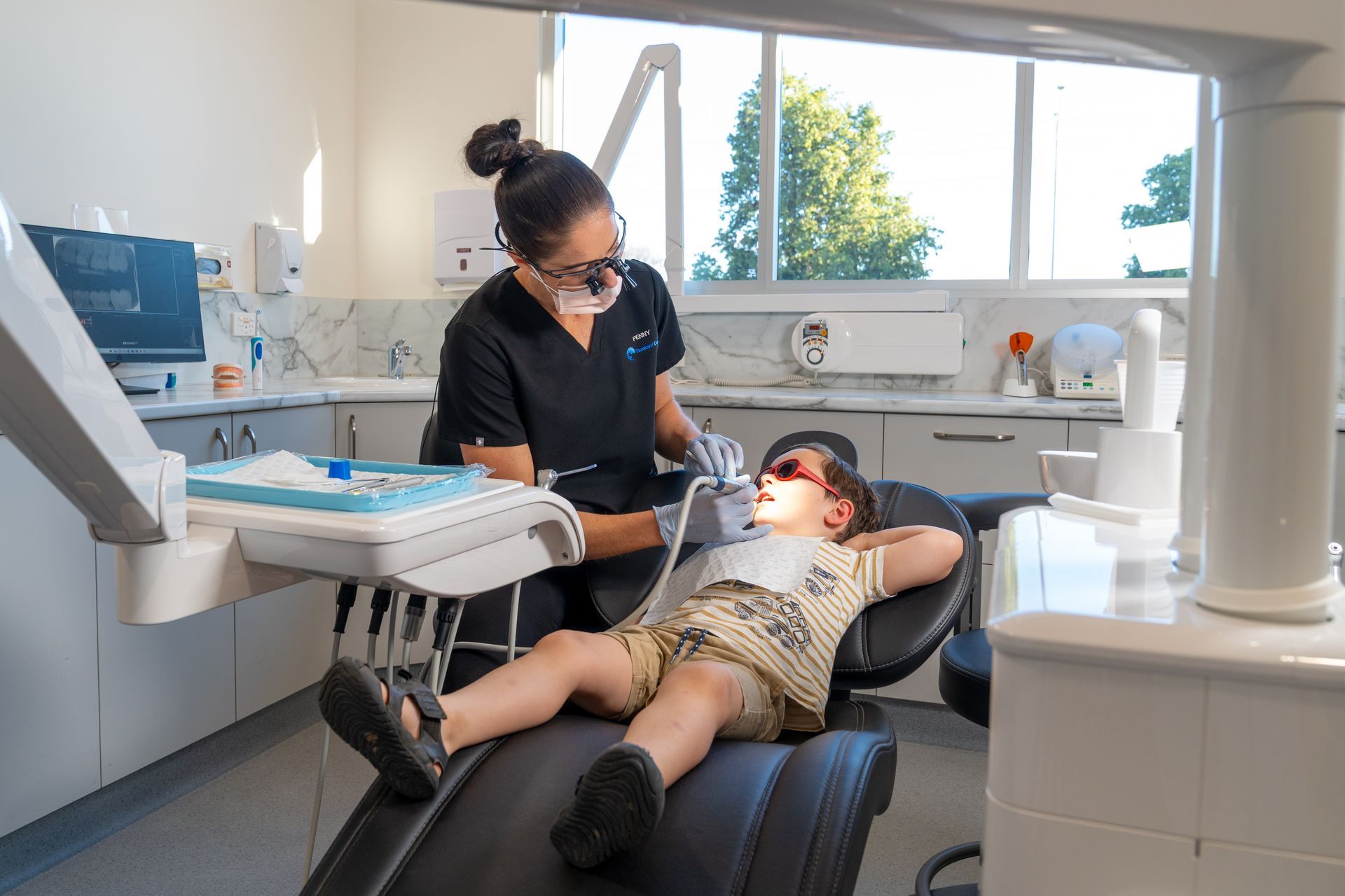 Boy learning to brush teeth with a model in a dentist's office.