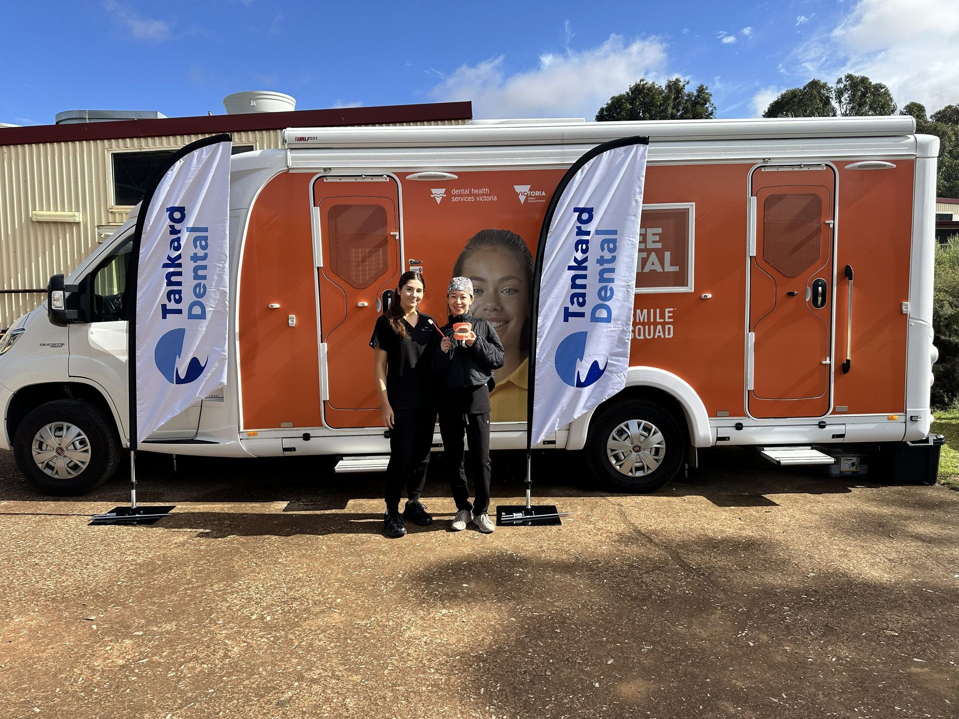 Boy in dental chair smiles at dentist with mask; blue and white setting.