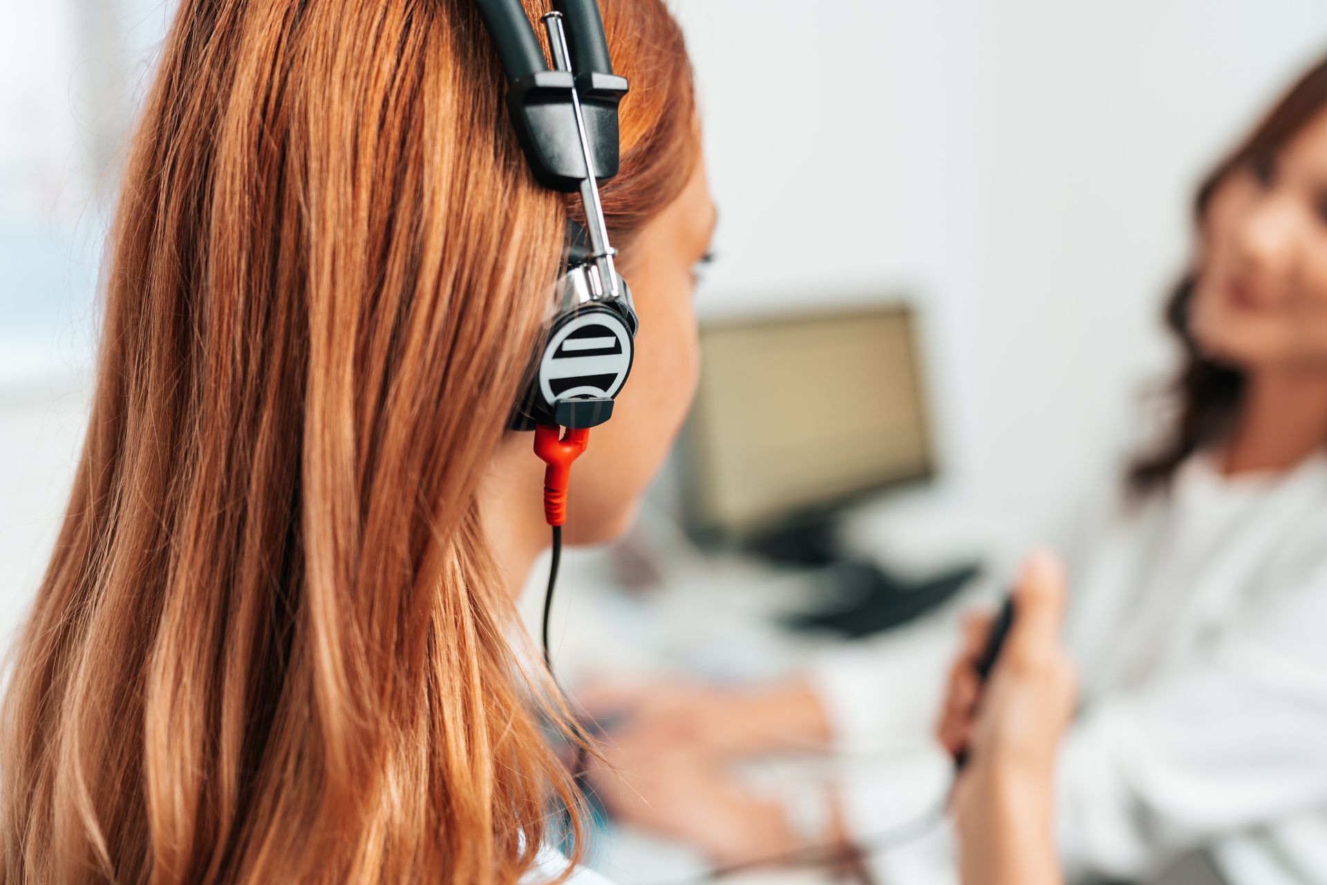 Woman wearing audiometric headphones during a hearing test with an audiologist