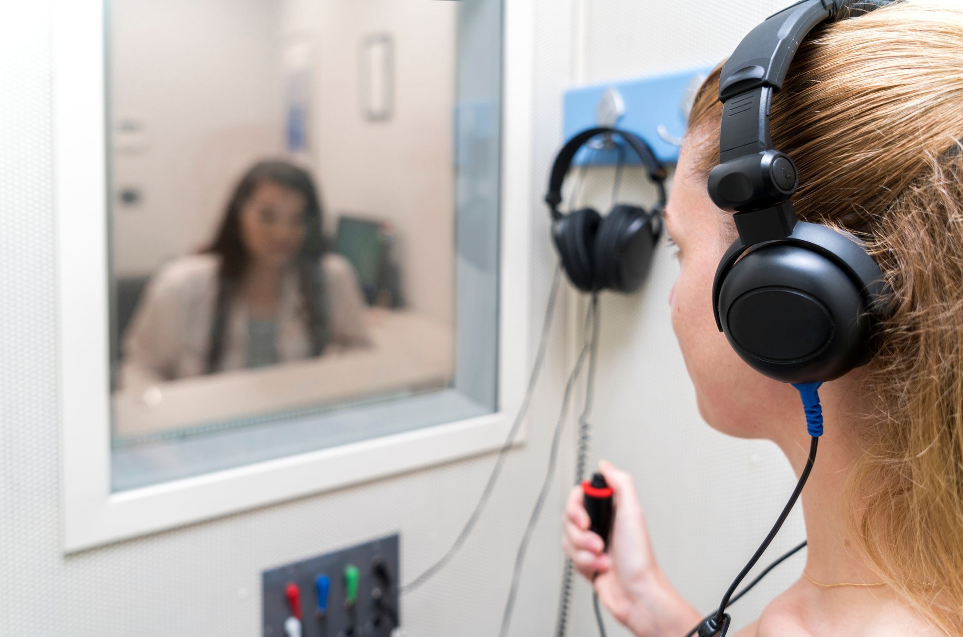 An audiologist woman is doing the hearing exam on a woman patient.