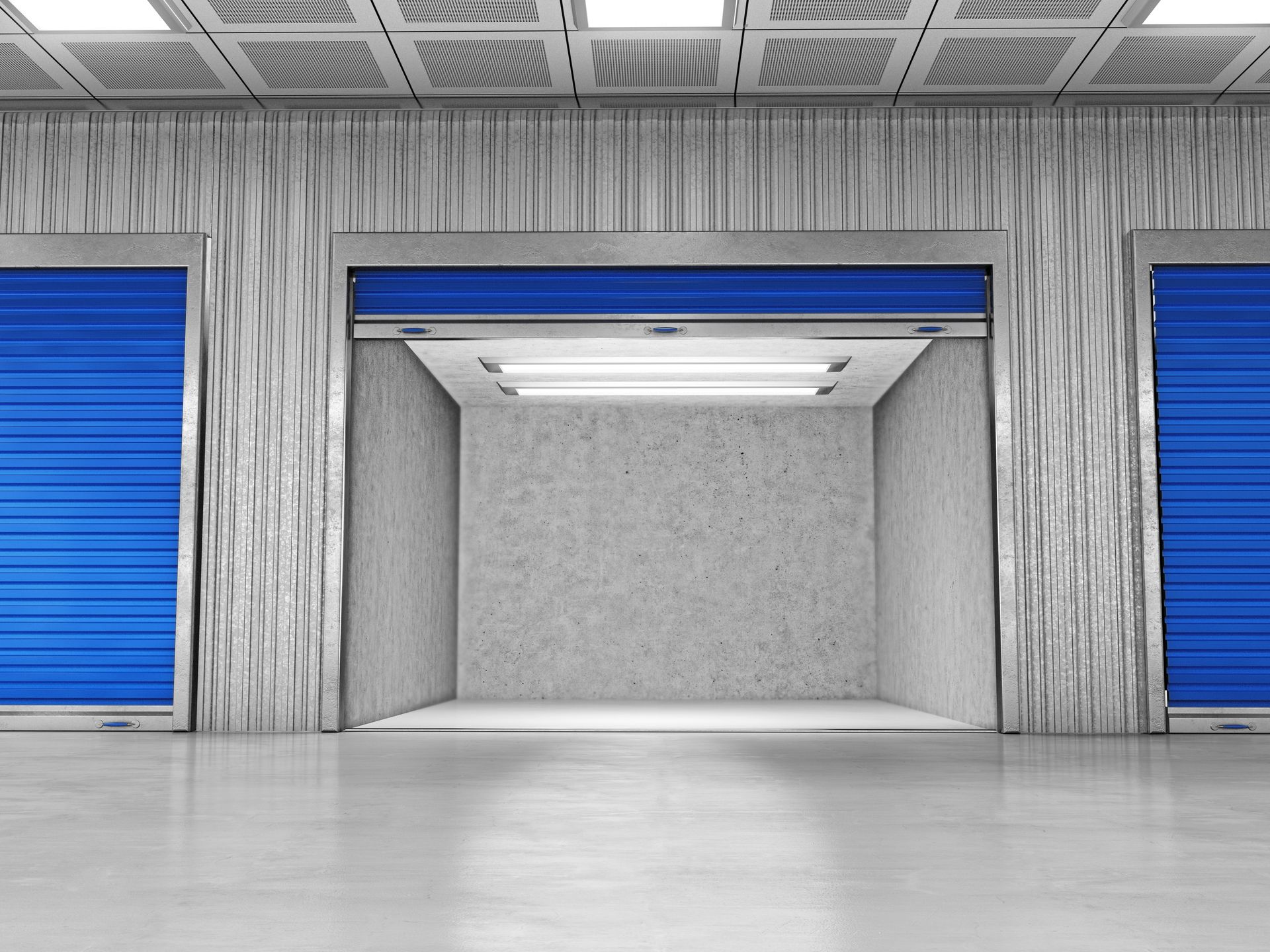 Three storage units, one open with a concrete interior, set in a facility with white, textured walls and blue roll-up doors.