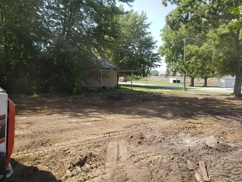 A house is sitting in the middle of a dirt field.