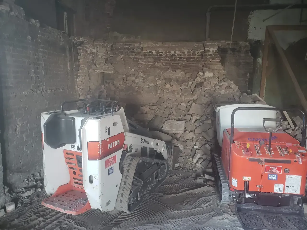 Two tractors are parked in a garage next to each other.