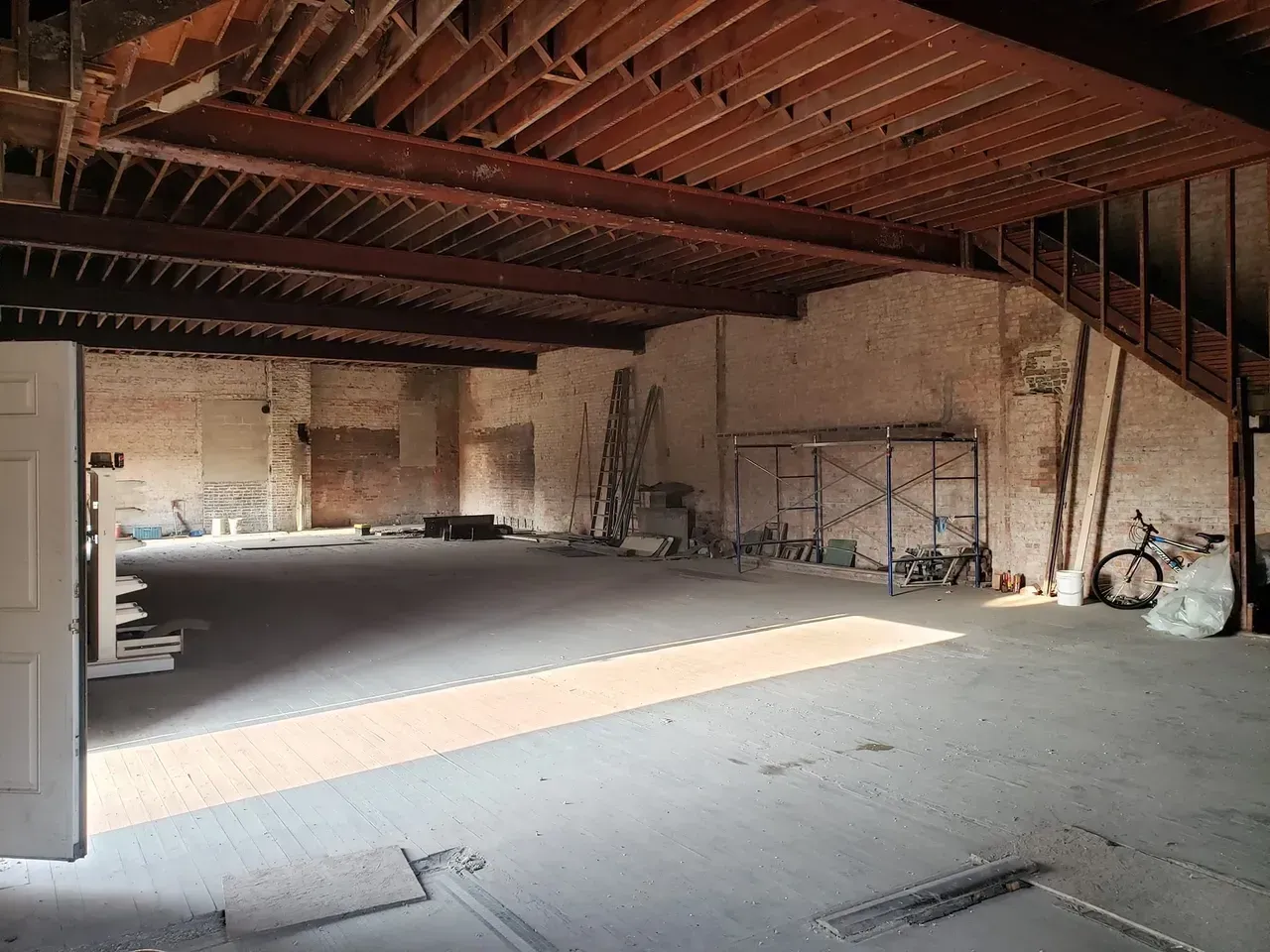 A large empty room with a wooden ceiling and stairs.