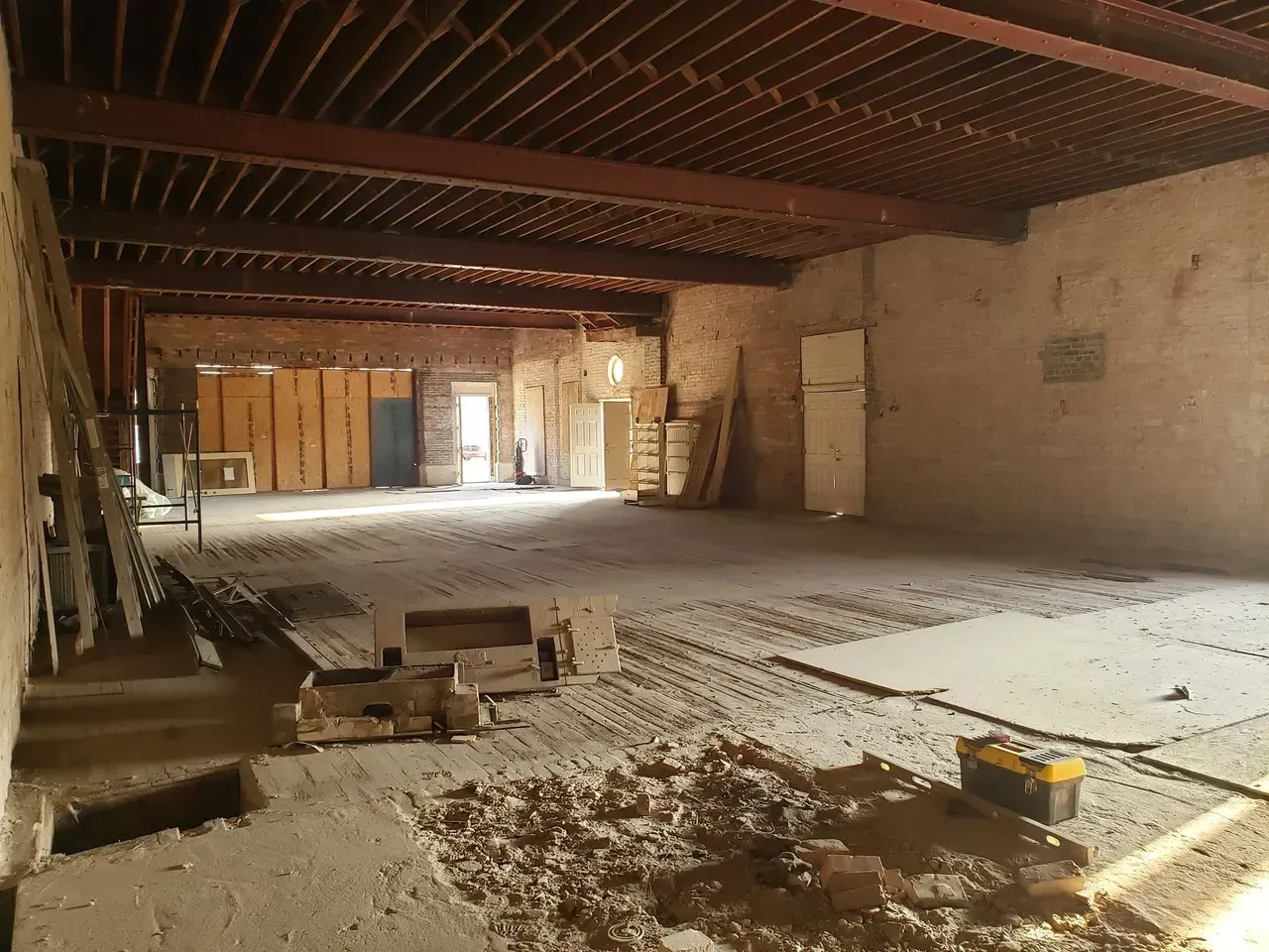 A large empty room with a wooden ceiling and a yellow toolbox on the floor.