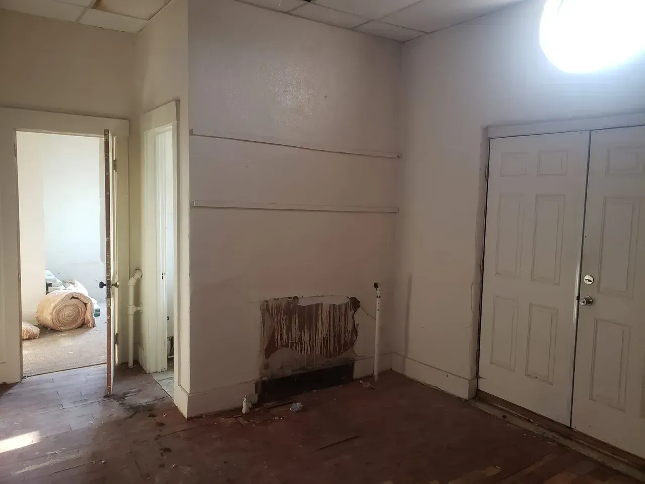An empty room with a fireplace and closets in a house.