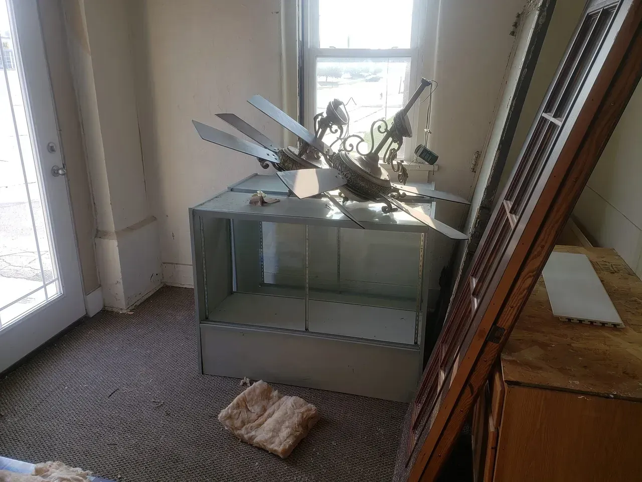 A room with a lot of junk on the floor and a window.