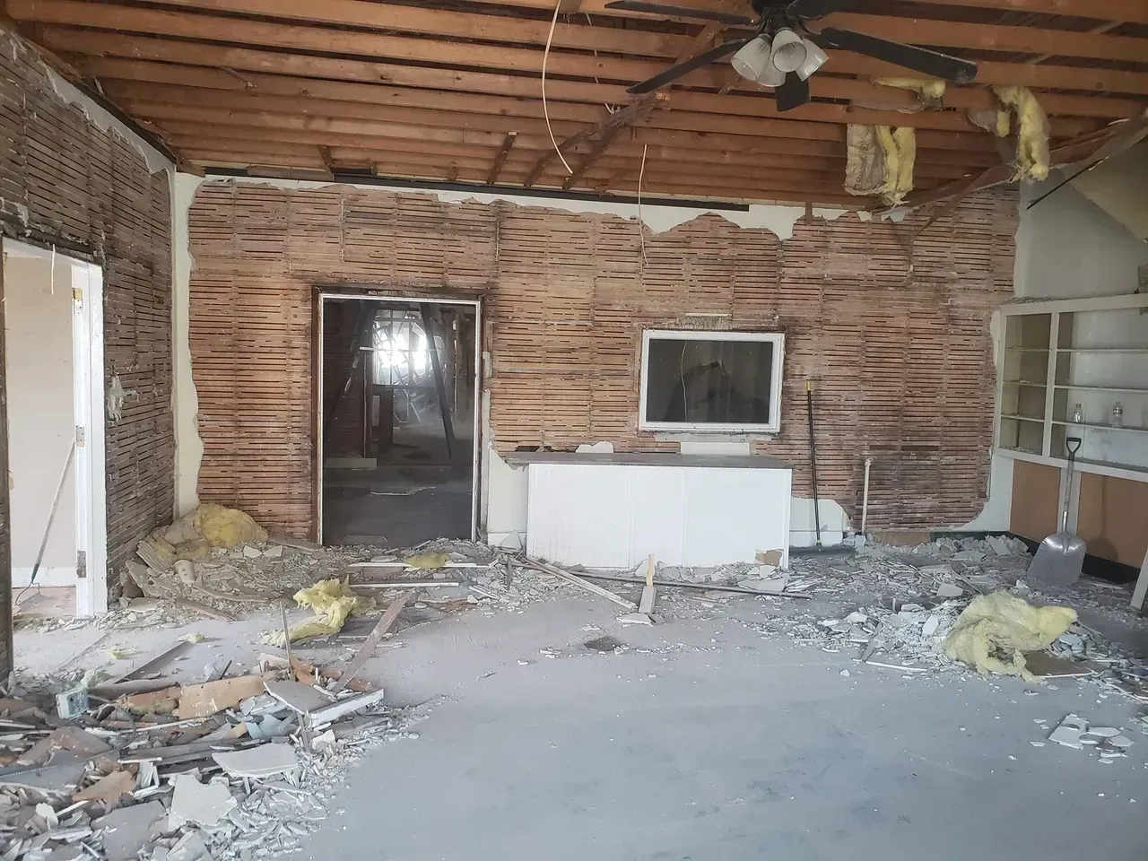 An empty room with a brick wall and a ceiling fan