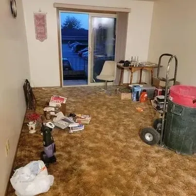A living room with a sliding glass door and a vacuum cleaner on the floor.