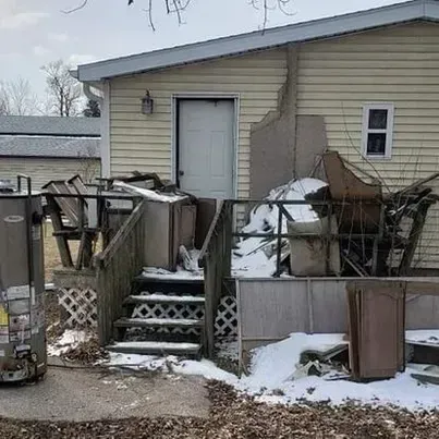 A mobile home with a deck and stairs in the snow.