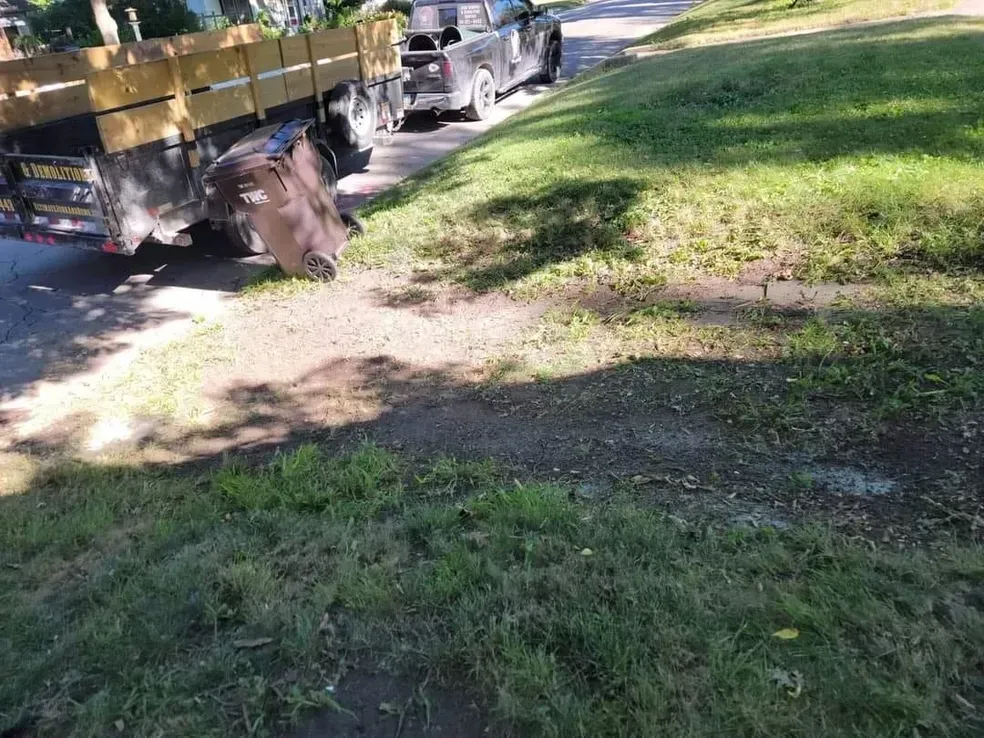 A truck is parked on the side of the road next to a grassy area.