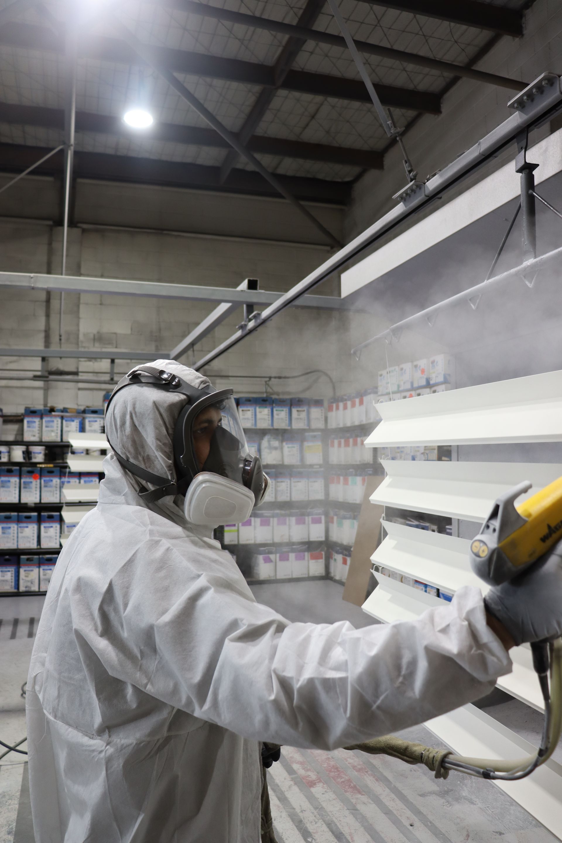 A person is painting a piece of metal in a room
